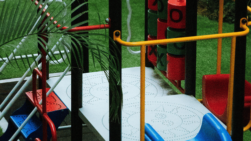 A colourful children's playground structure featuring a bright blue slide, climbing frames, and metal safety railings.