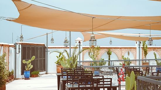 an overview of a rooftop restaurant with sun shade above the seating arrangements