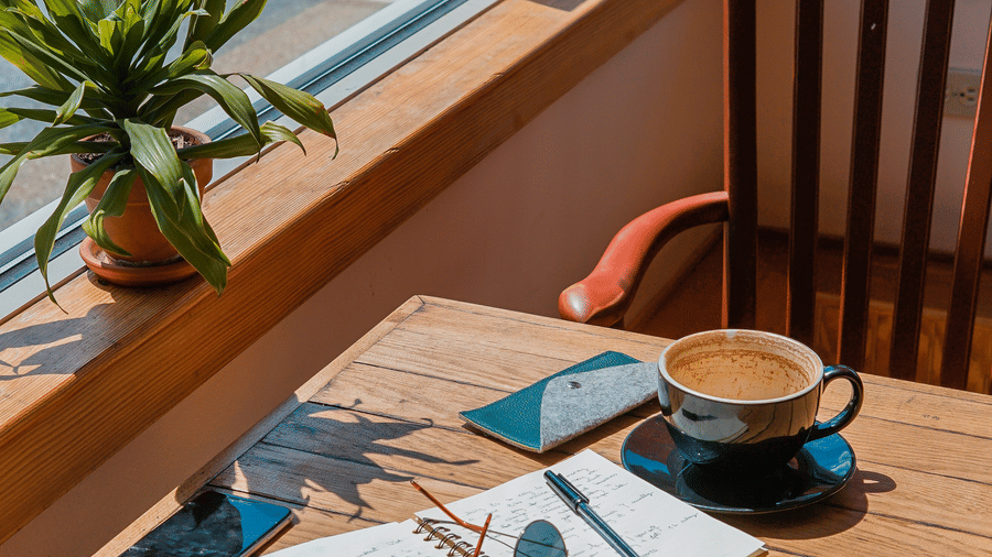 A cup of coffee a diary glasses and mobile phones on a table at a cafe