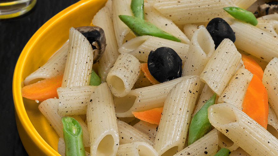 Creamy delicious pasta with vegetables, cheese served in a round bowl.