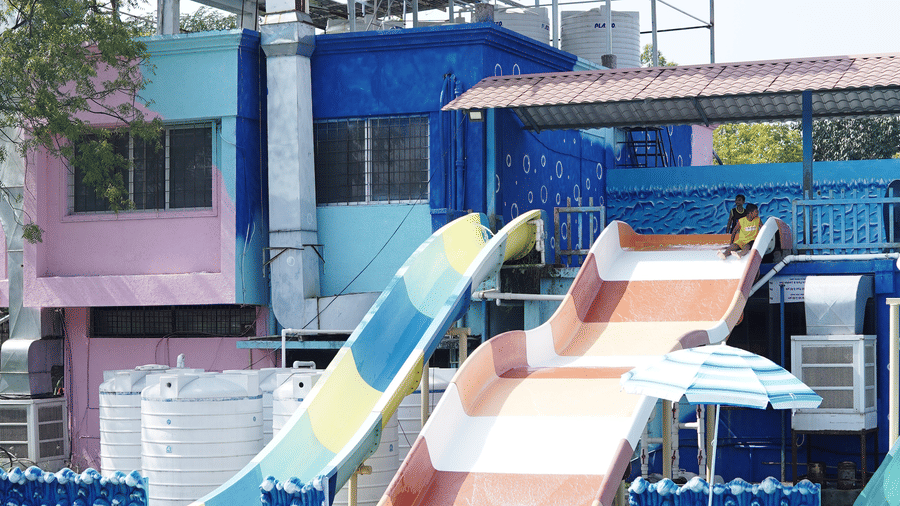 A large, blue and white water slide is emptying into a pool under a covered structure.
