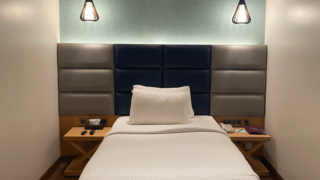 A comfortable bed with beautiful hanging light at SRM Hotel Maram Malai Nagar Chennai