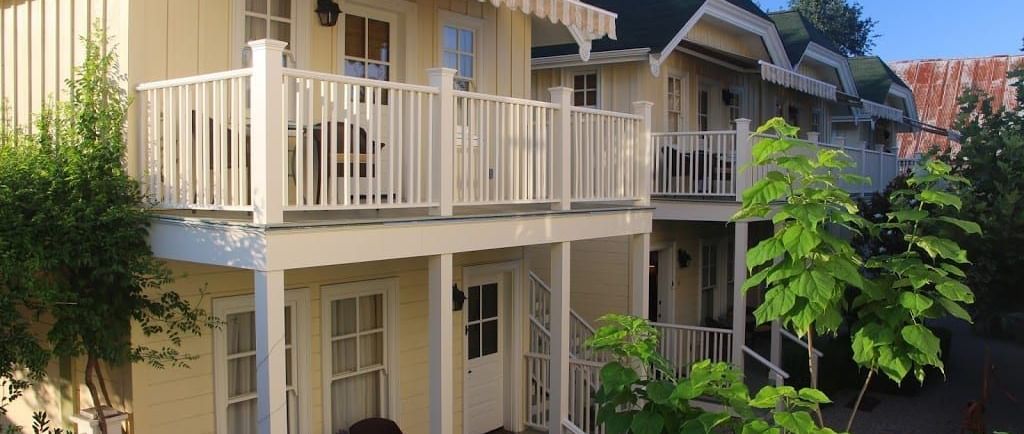 A two-storey house of Tallman Hotel with cream coloured walls and balconies depicting upper, and lower garden exterior. 