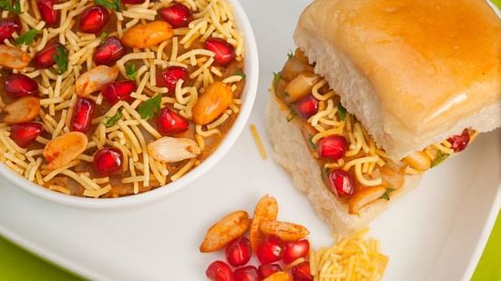plate of dabeli and pomegranate and sev filling in a bowl