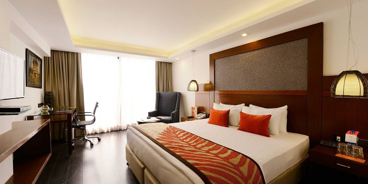 Deluxe Room at The Cunningham Hotel featuring a with a king size bed, warm lighting, wooden accents, a workspace, and a seating area