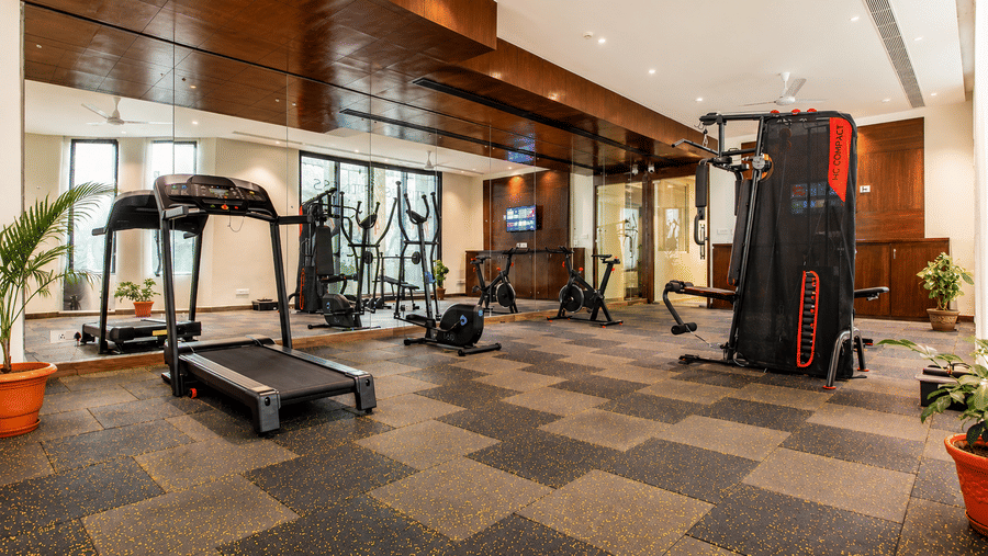 Fitness centre with treadmills, weight machines and wooden ceiling at Eastlynn Resort, Rishikesh.