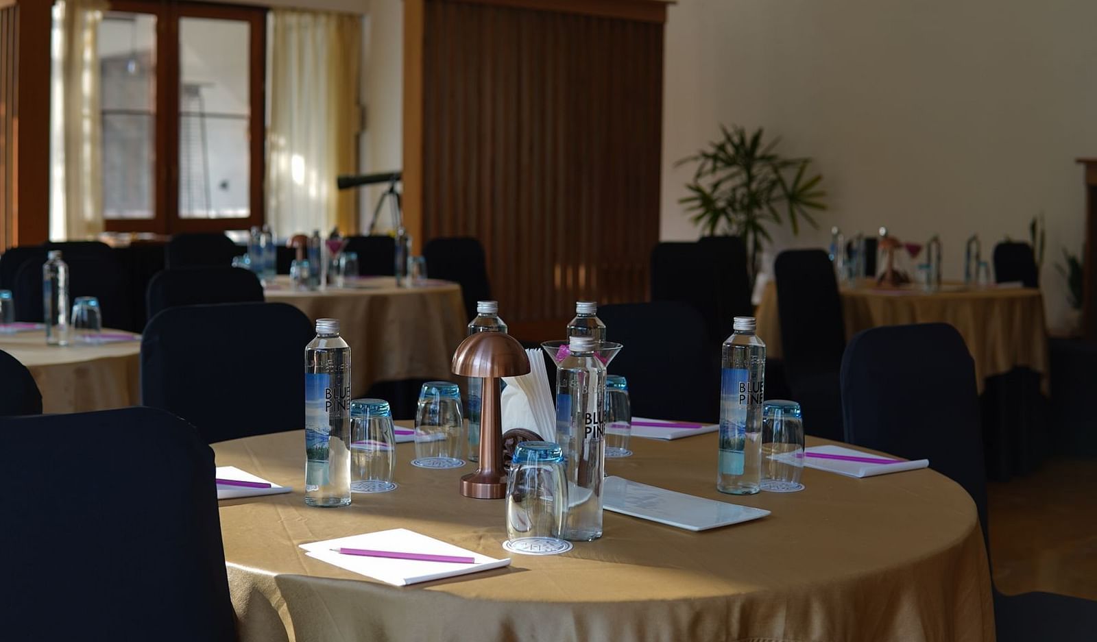 A conference room seating arrangement with a water bottles and notepads placed on the table at Saraca Resort & Spa Corbett