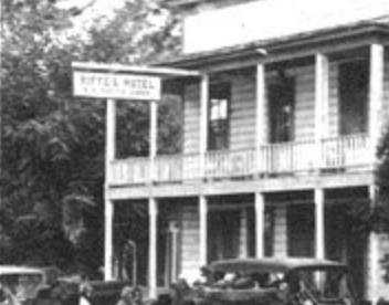 A classic black and white photo displays the historic Tallman Hotel building with cars parked outside, capturing a bygone era.