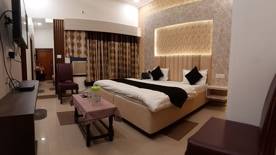 An image showcasing our Executive Rooms in Roorkee with a large king size bed placed in front a wall-mounted television - Motel Divine International, Roorkee