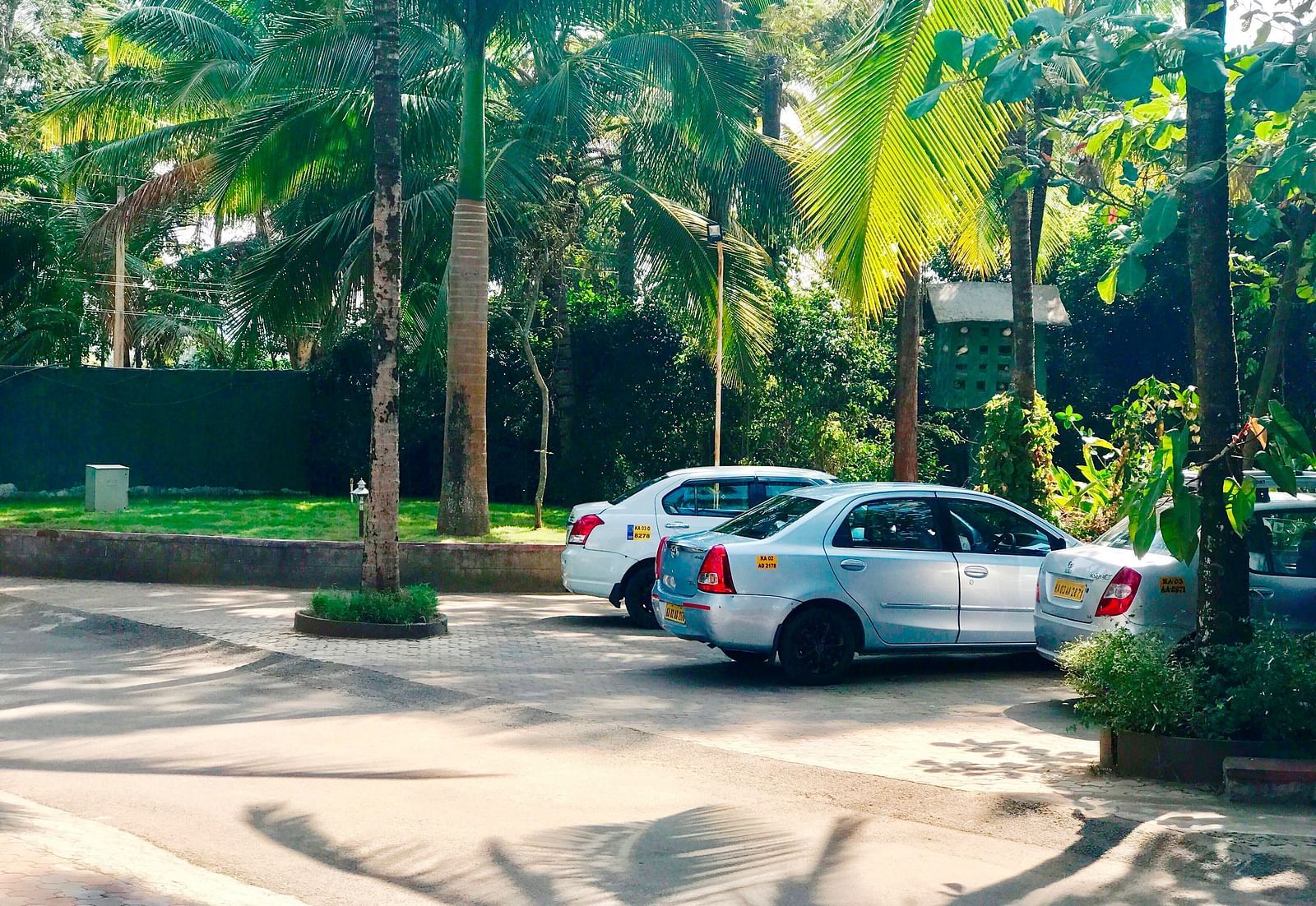 Image of an open area with two cars and trees around it at Parampara Resort & Spa, Kushalnagar.