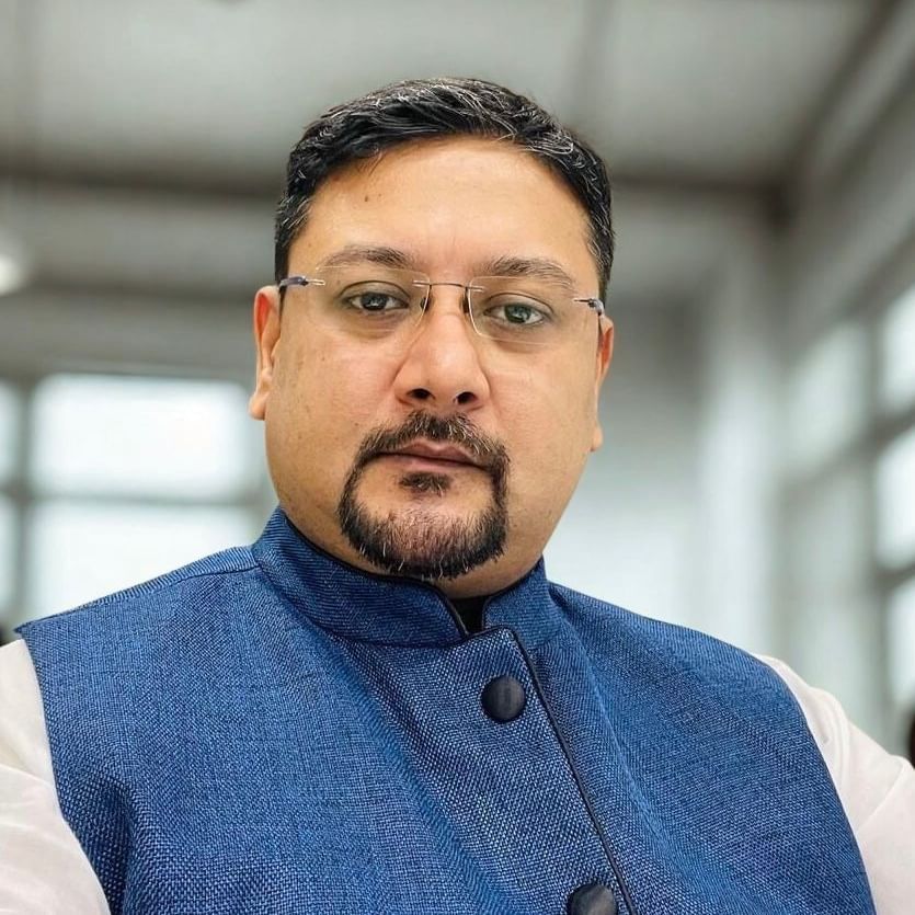 Portrait of Sudipta Sengupta wearing glasses and a blue jacket.