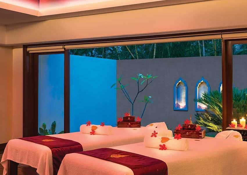 A tranquil spa treatment room with two massage beds, dim lighting, and an outdoor view | Spa | Regency Madurai by GRT Hotels