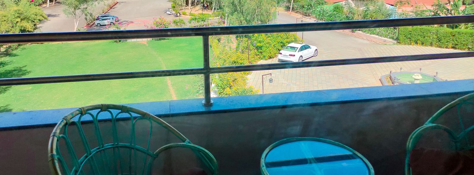  From a balcony, the view includes a lawn, trees, and mountains in the distance.- Bamboo Saa Resort & Spa, Udaipur