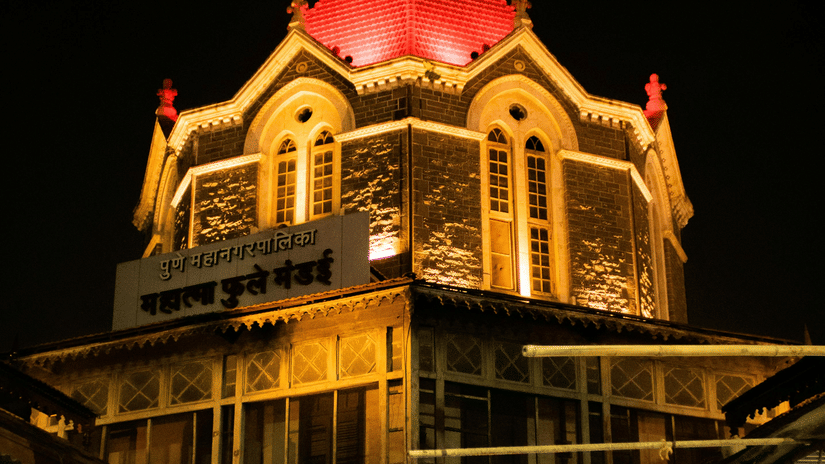 A building with a lit dome structure at night, showing architectural details and a dark sky in the background.