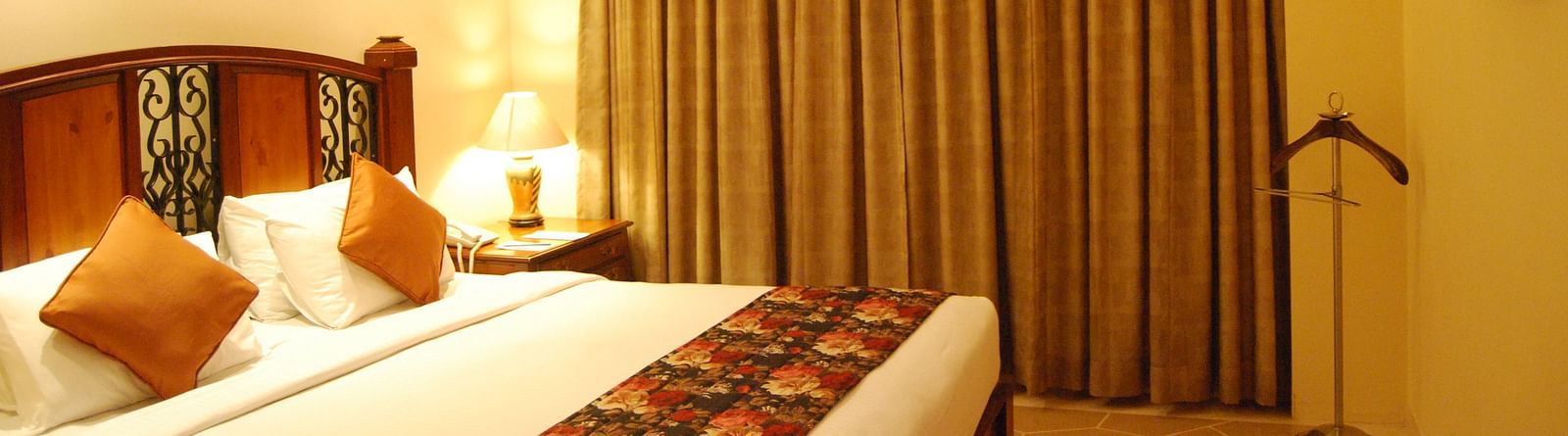 A king bed with a large mattress and cushions, facing a flatscreen TV in a well lit room