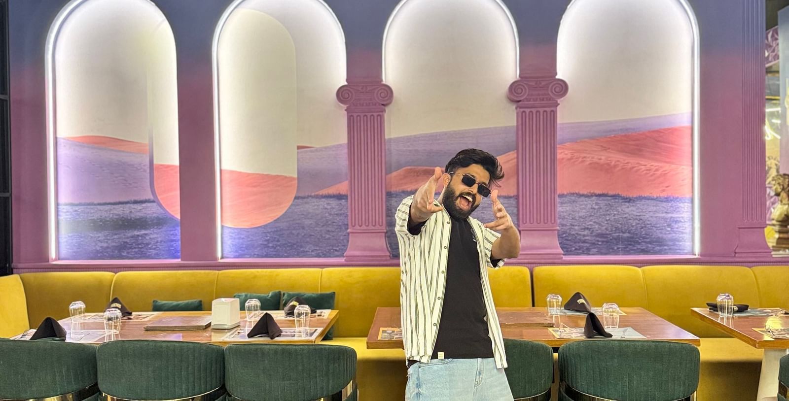 A person standing in the uniquely decorated interior of Themis Barbecue House, Ambala, with colorful arches and seating.