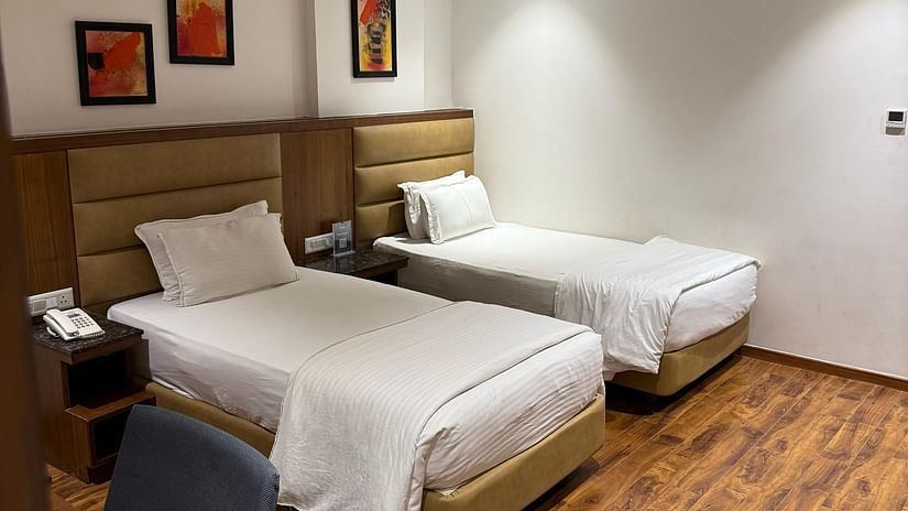 A bedroom at Kyriad Hotel, Gulbarga, with two made beds and artwork on the wall.