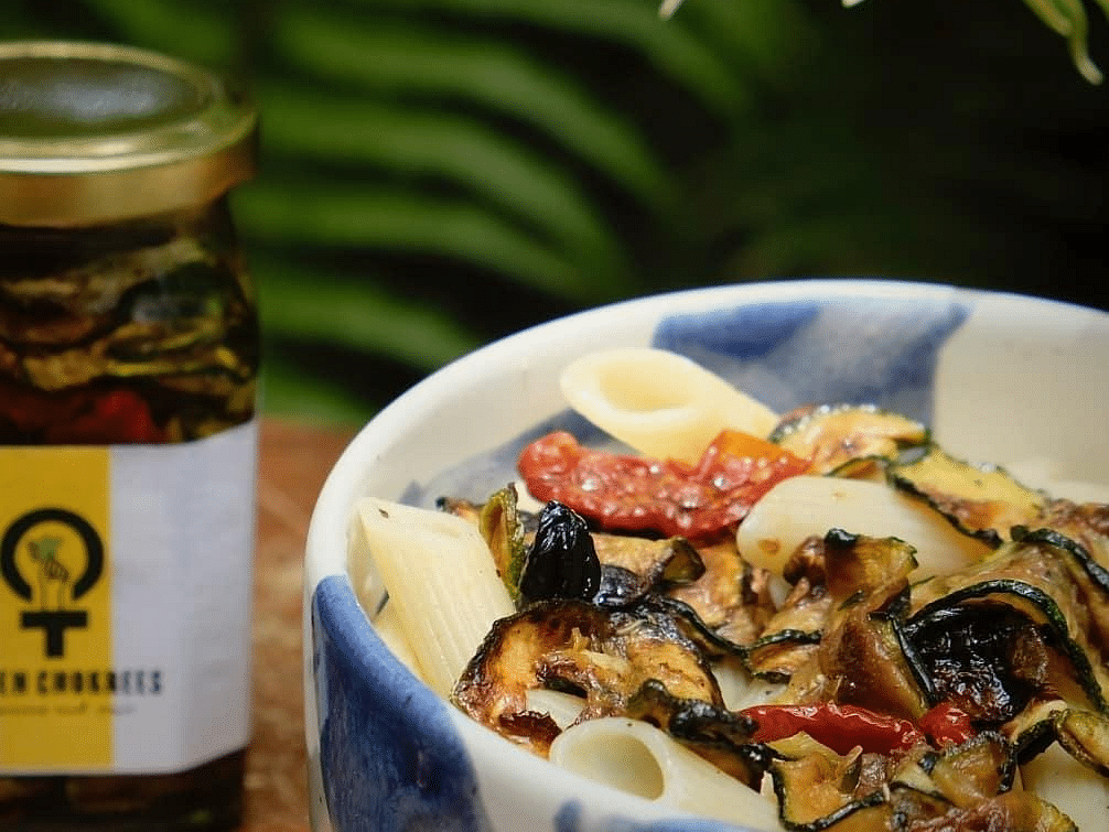 A bowl of food with a jar of pickle in the background
