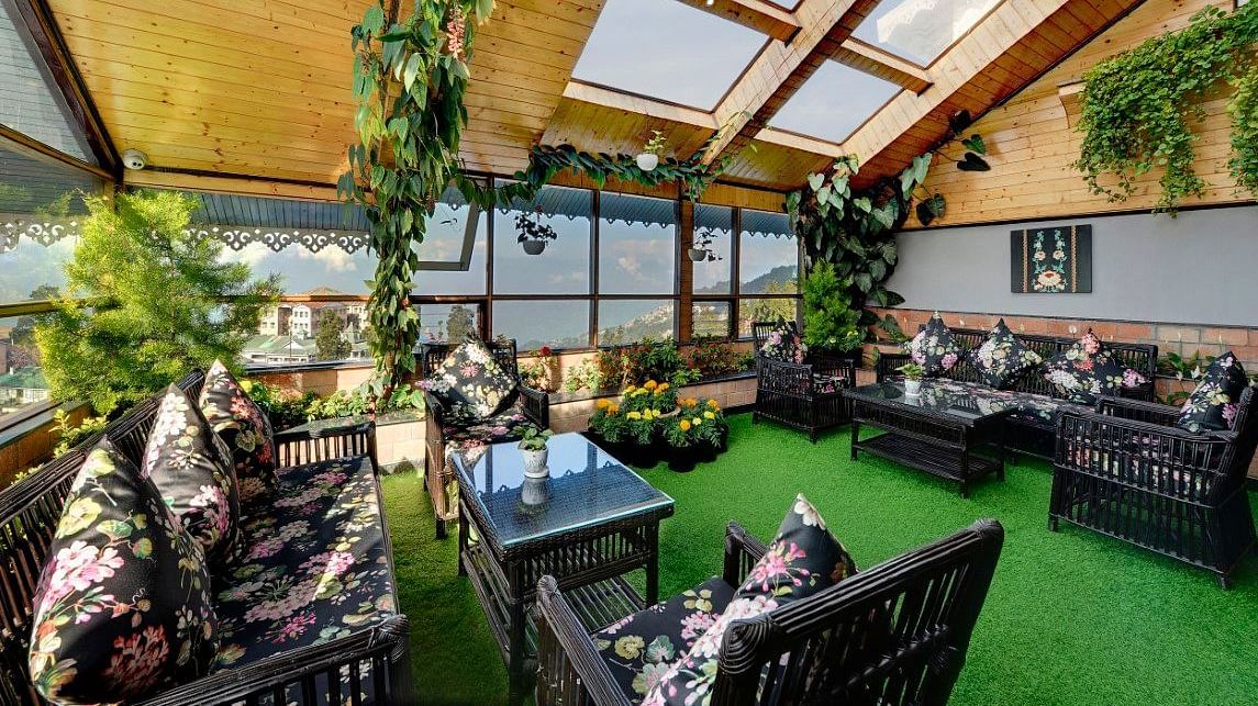 An image of the rooftop restaurant at Yashshree Mall Road, Darjeeling featuring decoration with plants and its seating arrangement