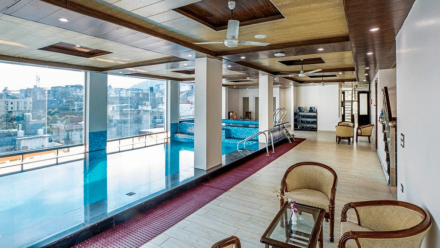 The lobby besides the swimming pool with a common seating area overlooking the city views from the glass window at Regenta Inn DLS.