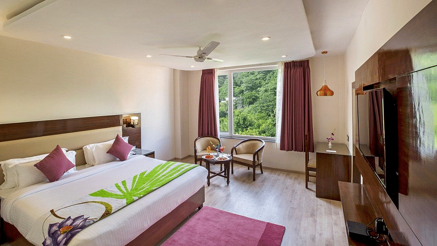 Full view shot of the Premium Room at Regenta Inn DLS featuring a double bed overlooking the lush green views from the window.