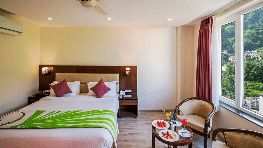 A double bed kept in the Premium Room with a common seating area in front of the window at Regenta Inn DLS.