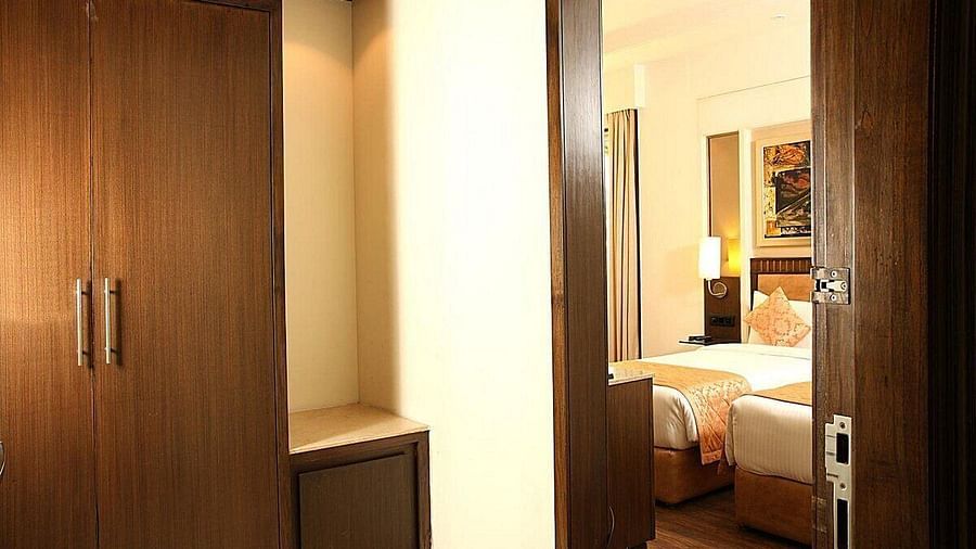 The Premium Twin Room entry view of twin beds with neatly arranged pillows, wooden bedside tables with lamps at Inde Signature Tower, Gurgaon