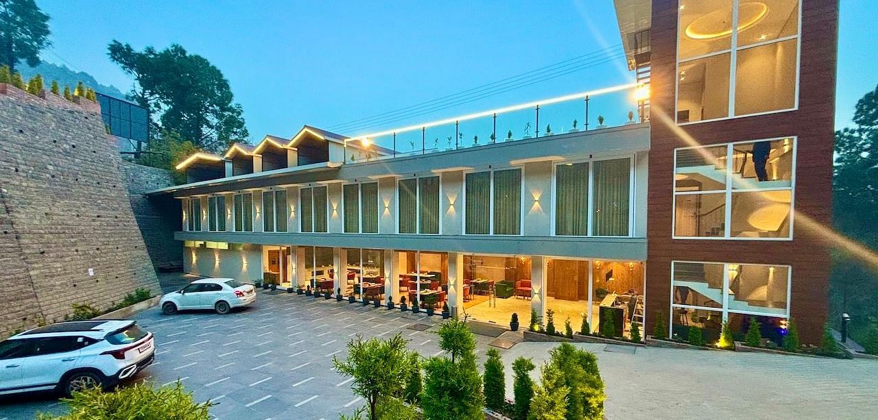 Exterior view of the ARNISA Boutique Hotel building with glass facade and neatly landscaped driveway