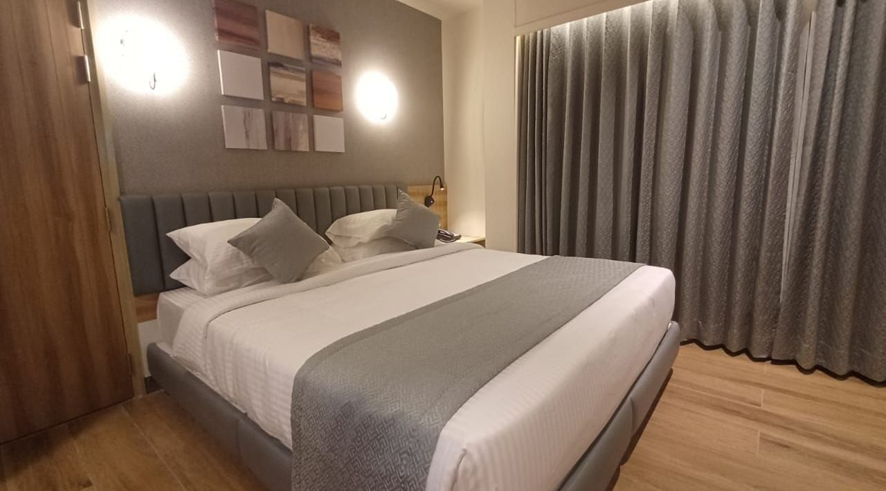 Family Suite at Hotel Paai, Hosur featuring a double size bed, a wardrobe, and a window with curtains drawn.