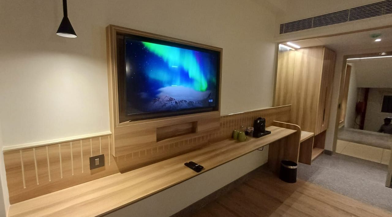Image of a living room with television and wooden floring at Hotel Raai, Hosur.