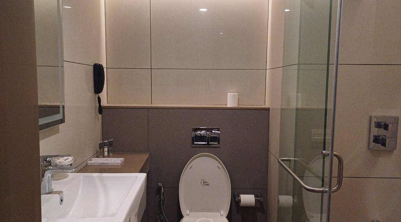 Image of a washroom with seperate shower space and modern amenities at Hotel Raai, Hosur.