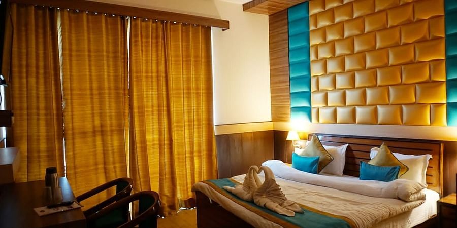 Double Bed Premium room with blue and white bed covers at Hotel Panchvati Inn, Joshimath 2