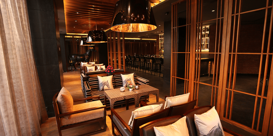  A dining space with chairs, tables, and cushions set in a warm lighting.