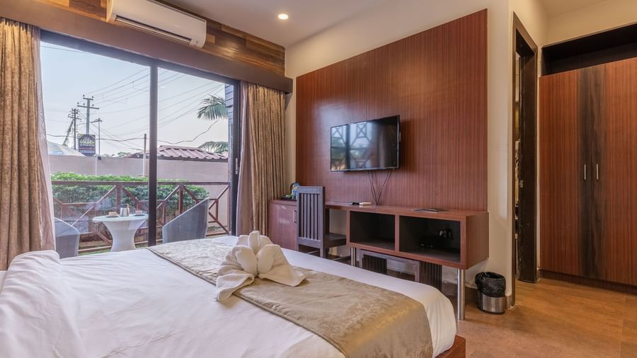 Corner view of Premium Room that is furnished with a plush queen size bed facing a wall-mounted TV, and drawn curtains showing view of the surroundings.