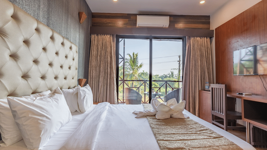 Side view of the Amara Premium Room at Amara Oceanfront Resort, Baga, showcasing the bed, balcony, and the view of the surroundings.