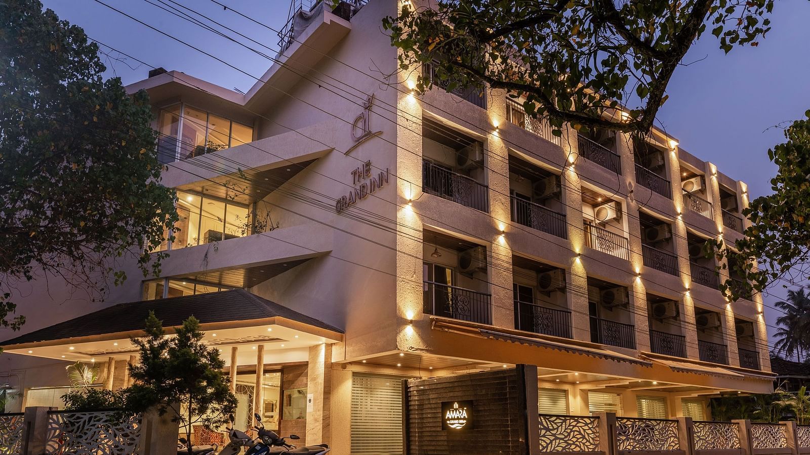 Night view facade of Calux Grand Inn, Calangute with trees on the side.