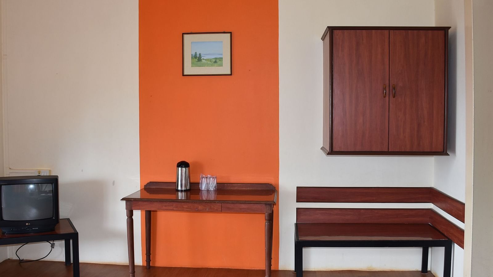 A room at Wind Chalet Resort featuring three sets of tables next to each other: one with a TV, another with essentials, and the third placed beneath a wall-mounted wooden cupboard.