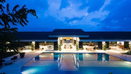 facade image of a property with a vast swimming pool in the foreground on a late evening