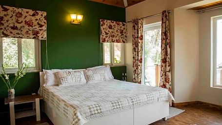 A large bed in a bedroom next to a nightstand and nightlamp above in 3 BHK at  at SOUTHGATE KASAULI BY ZENQ.