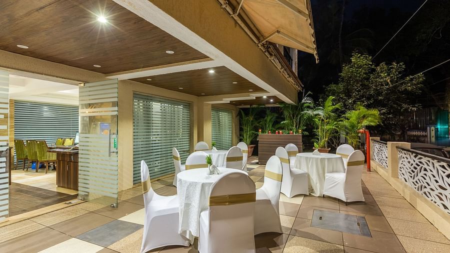 Image of an outdoor seating area with tables and chairs at Calux Grand Inn, Calangute.