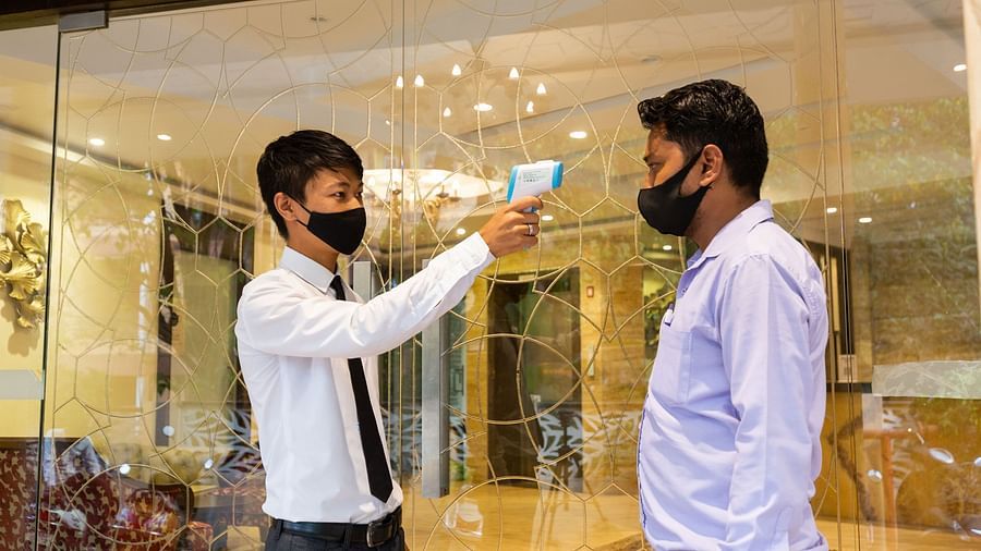 An image of a person using a temperature scanning tool on another person at Calux Grand Inn, Calangute.
