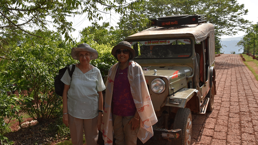 A couple poses next to a vintage jeep at Forest Escapes Koyna, possibly before an excursion.
