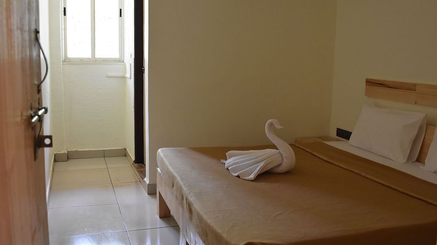 A side view of the room at Riverside Inn with a neatly made bed, a towel folded like a swan, and a pathway leading outside.