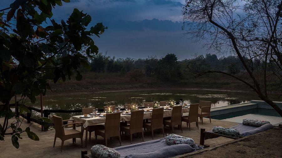 View of the dining setup near Swimming Pool at dusk at Saccharum Safari Lodge, Balaghat