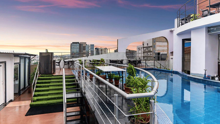 A full view shot of out rooftop restaurant and bar at Senses Hotel featuring a swimming pool along with beautiful evening sky in the background.