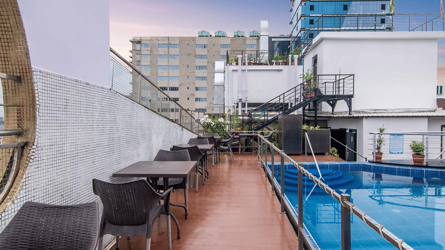 The passage way besides the rooftop swimming pool with chairs and tables arranged on the poolside - Senses Hotel