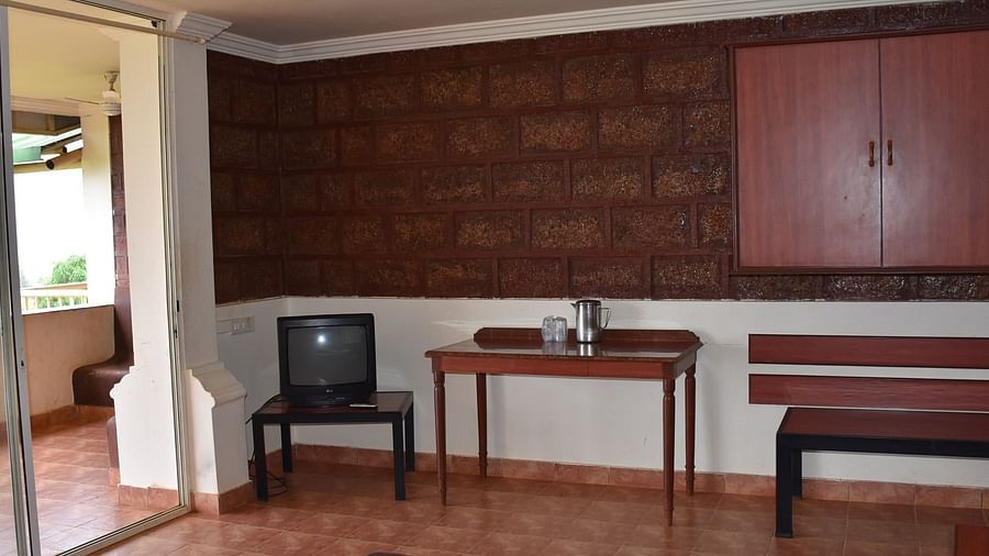 A room at Wind Chalet Resort featuring a small TV on a wooden table, with a larger table beside it holding essentials, and a wall-mounted wooden cupboard.