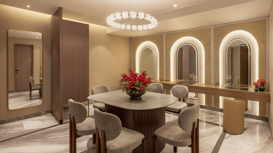 Bride room with 3 arched illuminated mirrors over a dressing counter, a round table with four chairs and a ring chandelier at The Residency Signature Madurai.