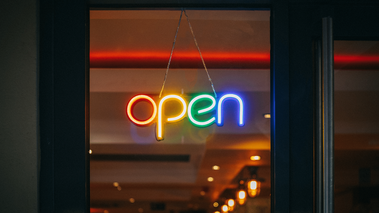 a sign with the words open written in neon lights on the door of an establishment