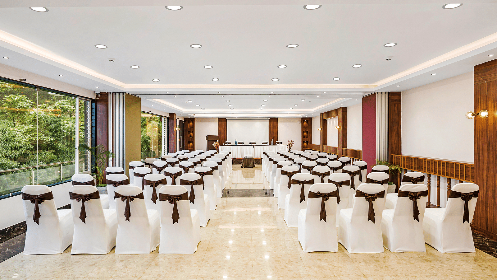 An image of a banquet space which is brightly lit with seating arrangement - GReaT Trails Kodaikanal By GRT Hotels